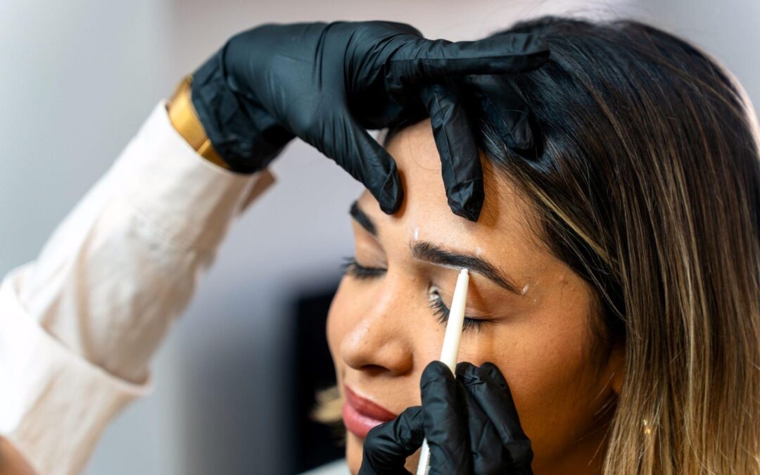Specialist mapping and shaping eyebrows with a pencil before brow lamination for natural feathered brows