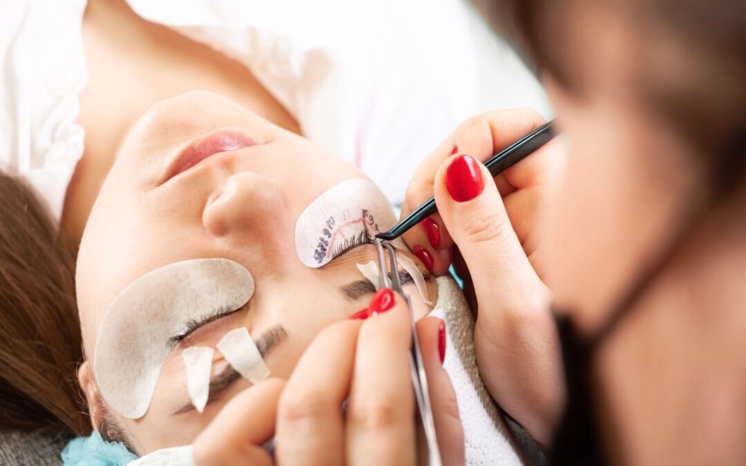 A young woman lying on a couch getting eyelash extensions in a beauty salon.
