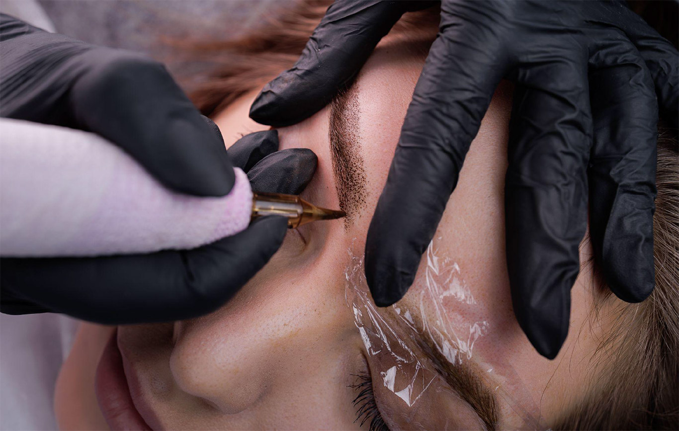 Close-up of a permanent makeup touch up on brows, refreshing pigment to keep results crisp between color boosts.